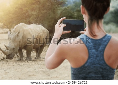 Back, rhino and woman with smartphone, nature and picture with memory, digital app and social media. Rear view, person and girl with cellphone, wildlife and animal with vacation, adventure or journey