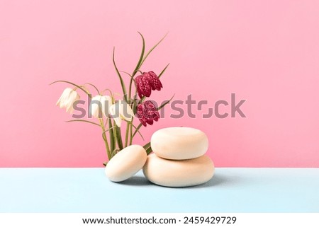 Wood stones and white and burgundy grouse flowers on blue table. Concept scene stage showcase for new product, banner, promotion sale, cosmetic, presentation