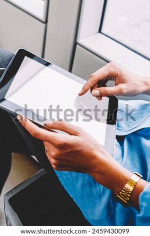 Cropped view of young woman choosing audio song in playlist downloaded on modern touch pad with earphones.Female person touching with finger on blank screen area of digital tablet using transport wifi