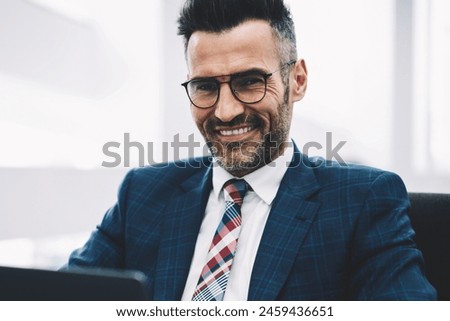 Half length portrait of successful businessman middle aged smiling at camera while working on accounting report at laptop computer connected to wireless 4g internet.Prosperous proud ceo checking mail Royalty-Free Stock Photo #2459436651