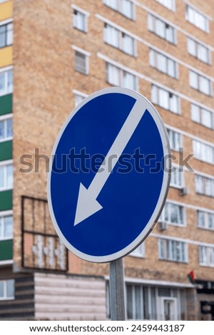 a blue and white sign with an arrow pointing to the right in front of a building . High quality