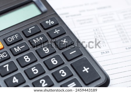 A closeup of a calculator, a peripheral input device, on top of a sheet of paper, office equipment often used with a computer keyboard or personal computer for calculations Royalty-Free Stock Photo #2459443189