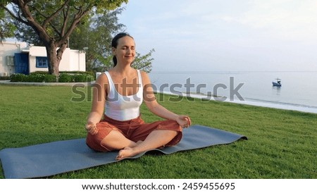 Young woman meditating in lotus pose by the coast in the morning, harmony with nature