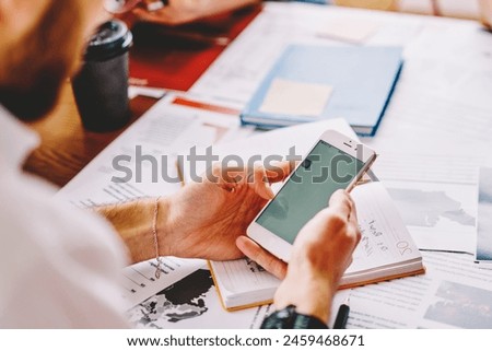 Cropped view of hipster student watching videos in blog on smartphone and chatting online with followers.Young man reading notification on modern cellular with moc up area using 4G connection Royalty-Free Stock Photo #2459468671