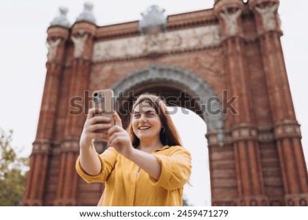 Young female tourist visiting Barcelona triumphal arch. Traveling woman taking selfie outdoors. Banner of travel, tourism and vacation in city. Use technology concept, Traveling Europe