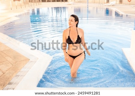 A cheerful  woman in the pool on a sunny day. Beautiful woman having fun in the pool. summer vacation.