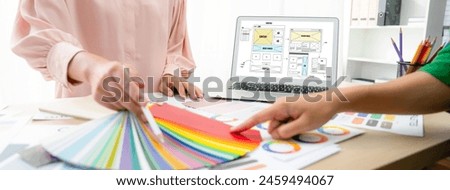 Cropped image of interior designer chooses color from color swatches while laptop displayed website wireframe designs for mobiles app and website. Creative design and business concept. Variegated.