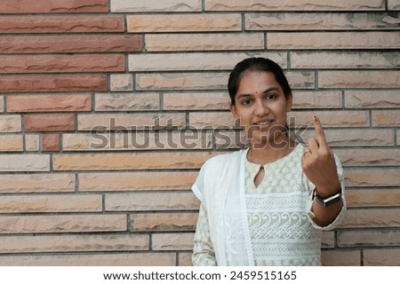 Picture of an Indian woman showing her finger after casting vote in election. Royalty-Free Stock Photo #2459515165