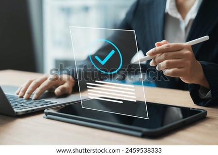 businesswoman is typing on a laptop and tablet, with a check mark on the tablet. The check mark represents a positive outcome or approval
