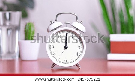 Classic white clock on a table. The clock hand points at 12:00, 00:00 close up photo interior