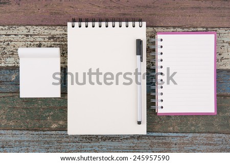 Notebook paper and school or office tools on vintage wood table  for background