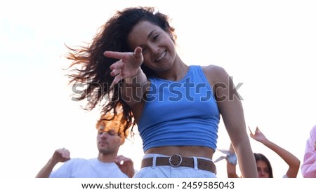 Close up of cheerful young attractive woman dancing and jumping having fun at summer party on a roof. Happy beautiful female dances and smiling. People dance on background.