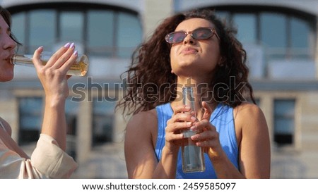 Young stylish people relaxing outdoors at party on sunny day with drinks. Close up of joyful positive youth drinking beer and dancing in good mood. Leisure. Summertime vibe