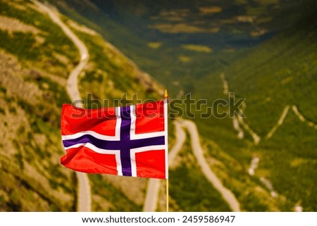 Norwegian flag and Trolls Path Trollstigen winding scenic mountain road in Norway Europe. National tourist route. Royalty-Free Stock Photo #2459586947
