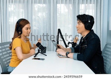 Smiling radio influencer host holding tablet wearing headphones interview woman speaker social media online live streaming channel with talking to share link at morning at studio record. Infobahn.