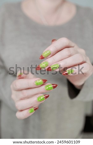 Female hands with long nails and green and brown french manicure	