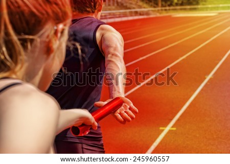 Relay race handing over from woman to man Royalty-Free Stock Photo #245960557