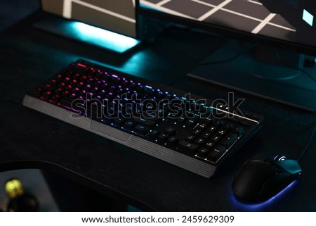 Playing video games. Computer keyboard with RGB lighting and mouse on table indoors