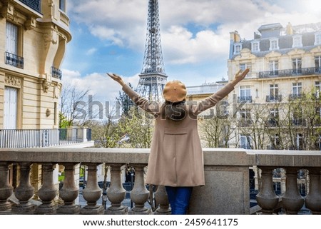 A happy tourist woman with a french beret hat looks at the beautiful cityscape of Paris, France, with Eiffel Tower