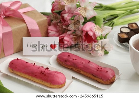 Tasty breakfast served in bed. Delicious desserts, flowers, gift box and card with phrase I Love You on tray, closeup
