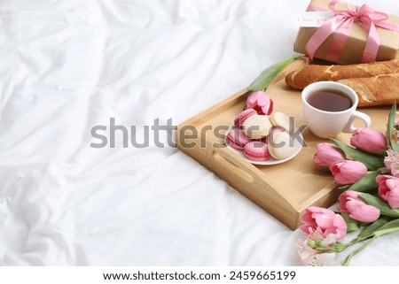 Delicious breakfast, flowers, gift box and card with phrase I Love You on bed, space for text