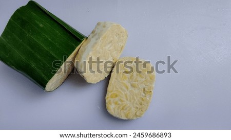 Tempe, fermented soybeans traditionally wrapped in banana leaves, a typical Indonesian food. White isolated photo with copy paste area for text. Royalty-Free Stock Photo #2459686893