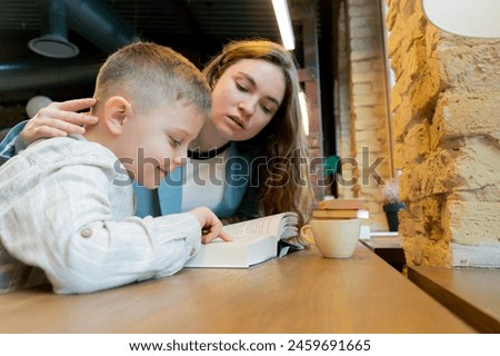 close up in bookstore near the window a young mother sits teaching her son to read child development