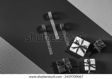 White and black gift boxes and black decorative tapes on black packaging paper with space for text