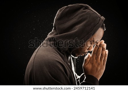 Contemplative man in hoodie with head bowed in thought