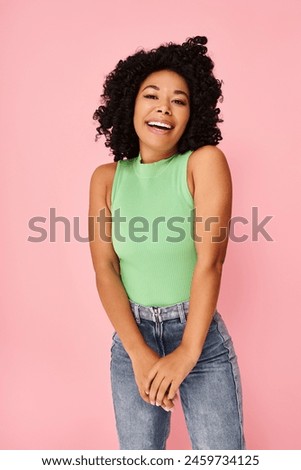 A woman in a green shirt and jeans strikes a pose for a picture.