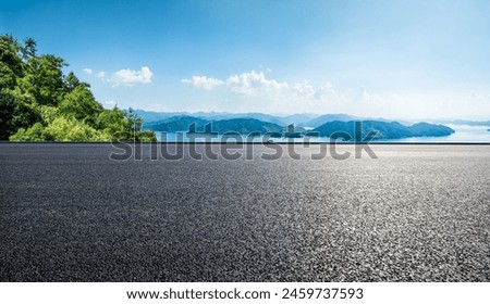 Asphalt road and lake with mountains nature landscape on a sunny day. Beautiful coastline in summer season.
