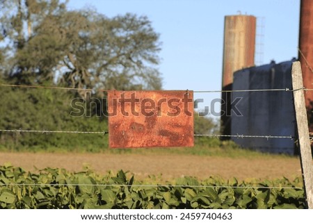 Rusty metal sign on a fence in a farm field