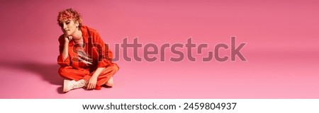Extraordinary woman sitting gracefully on pink surface with matching background.