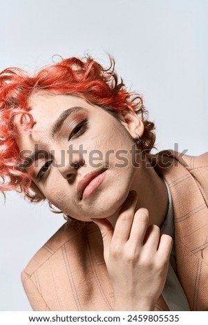 A vibrant woman with red hair strikes a confident pose.