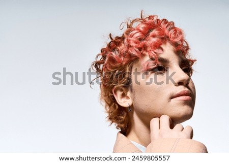 A vibrant woman with red hair poses stylishly.
