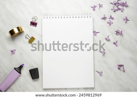 Home office desktop with top view, decorated with lilac flowers, notepad and pen, paper clips and clips with a layout of the place to copy.