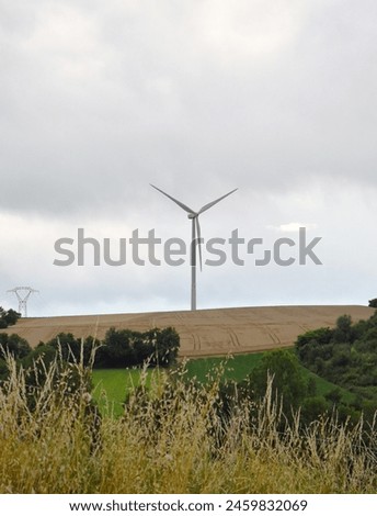 Vertical shot of rural landscape, with a isolated wind turbine erected in the middle of the fields. Royalty-Free Stock Photo #2459832069