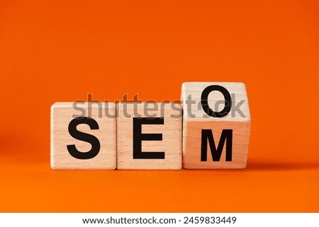 The word SEO changing in SEM, written in wooden cubes on beautiful orange background, Concept for Search Engine Optimization and Search Engine Matketing, copy space