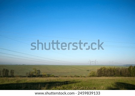 Blurry picture of grassy field under blue sky with power lines in background