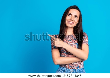 Photo portrait of pretty young girl point look empty space wear trendy colorful clothes isolated on blue color background