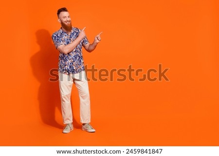 Full size photo of cheerful man with red long beard wear stylish shirt indicating at sale empty space isolated on orange color background