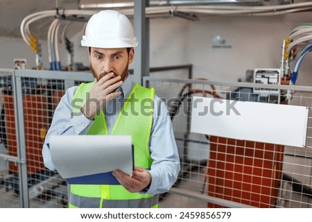 industrial engineer inspecting manufacturing plant looking puzzled and worried Royalty-Free Stock Photo #2459856579