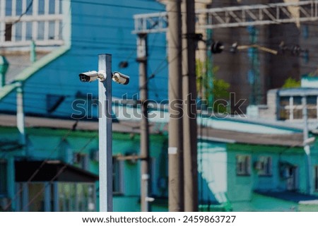 Two opposing surveillance cameras on a metal pole against building backdrop Royalty-Free Stock Photo #2459863727