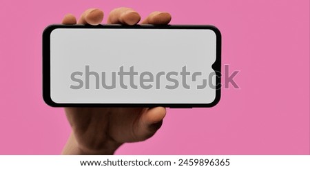 A striking image of a hand holding a smartphone with a blank screen against a vibrant pink background. Perfect for showcasing apps or mobile technology with a fresh, modern aesthetic