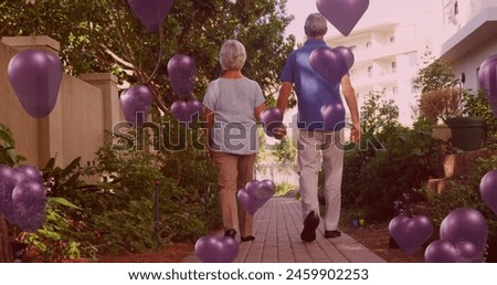 Image of purple hearts over couple in love walking and holding hands. Valentine's day, love and romance concept digitally generated image.