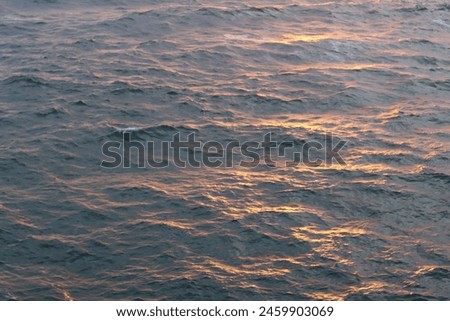 Dawn at sea, with waves tinged with golden sunlight Royalty-Free Stock Photo #2459903069