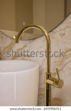 A gold faucet adorns a sleek rectangular sink in a bathroom, The elegant plumbing fixture enhances the overall aesthetic of the space
