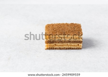 slice of vanilla cake with jam filling, thin layers of vanilla and chocolate cake with jam filling on a white background Royalty-Free Stock Photo #2459909559