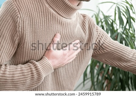 young man experiences experiences sudden chest pain behind sternum, clutching chest, Arterial hypertension, Myocarditis or Arrhythmia, heart disease experiences, Risk factors Royalty-Free Stock Photo #2459915789