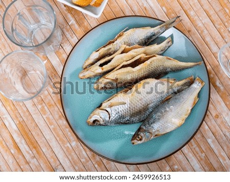 Dried salted caspian roach fish on light wooden background, traditional russian snack